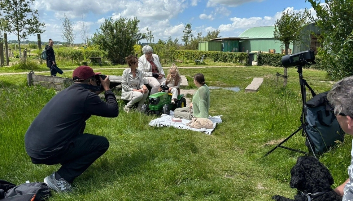 Fotograaf in het gras die een familie fotografeert